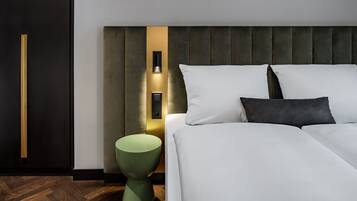 Un dormitorio moderno con una cama grande, un taburete verde decorativo e iluminación empotrada en la pared.