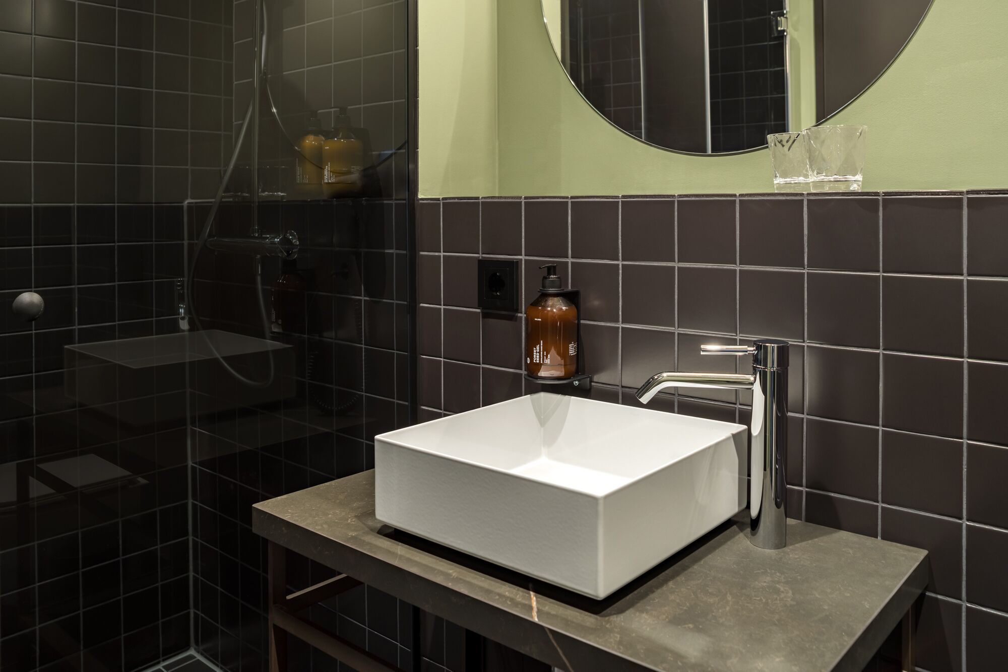 Une salle de bain moderne avec un lavabo blanc, un miroir et un espace douche.