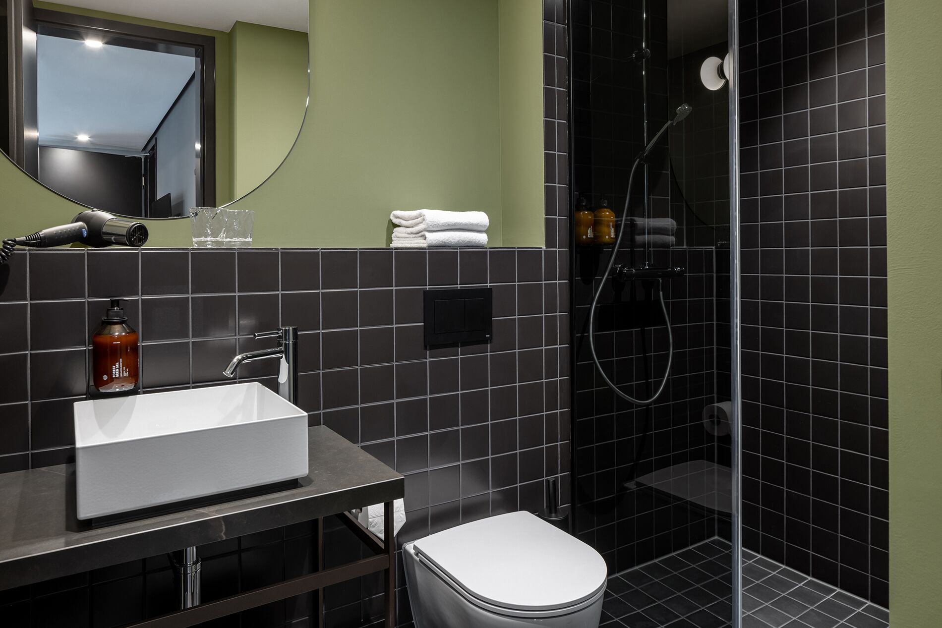 A modern bathroom with a white sink, a toilet, and a glass-enclosed shower.