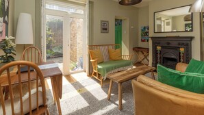 Un salon chaleureux avec une cheminée, un coin repas avec des meubles en bois et une vue sur l’extérieur.