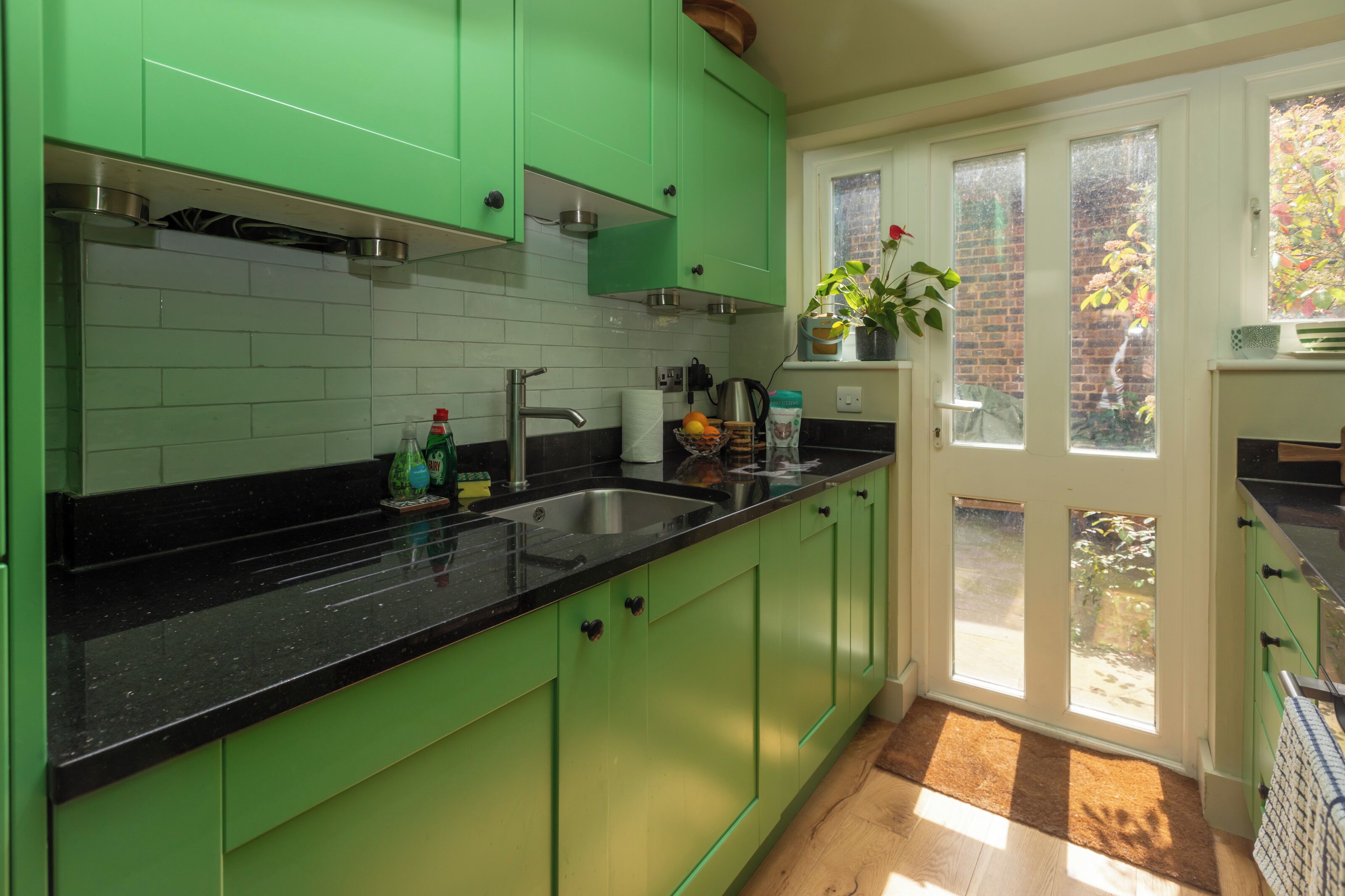 A kitchen with green cabinets, a black countertop, and a window with a view of the outside.