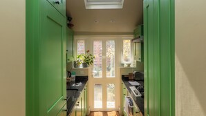 Une cuisine étroite avec des meubles de couleur verte, une lucarne et une vue sur l’extérieur.