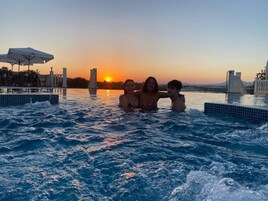 Piscina ao pôr do sol com três pessoas na água.