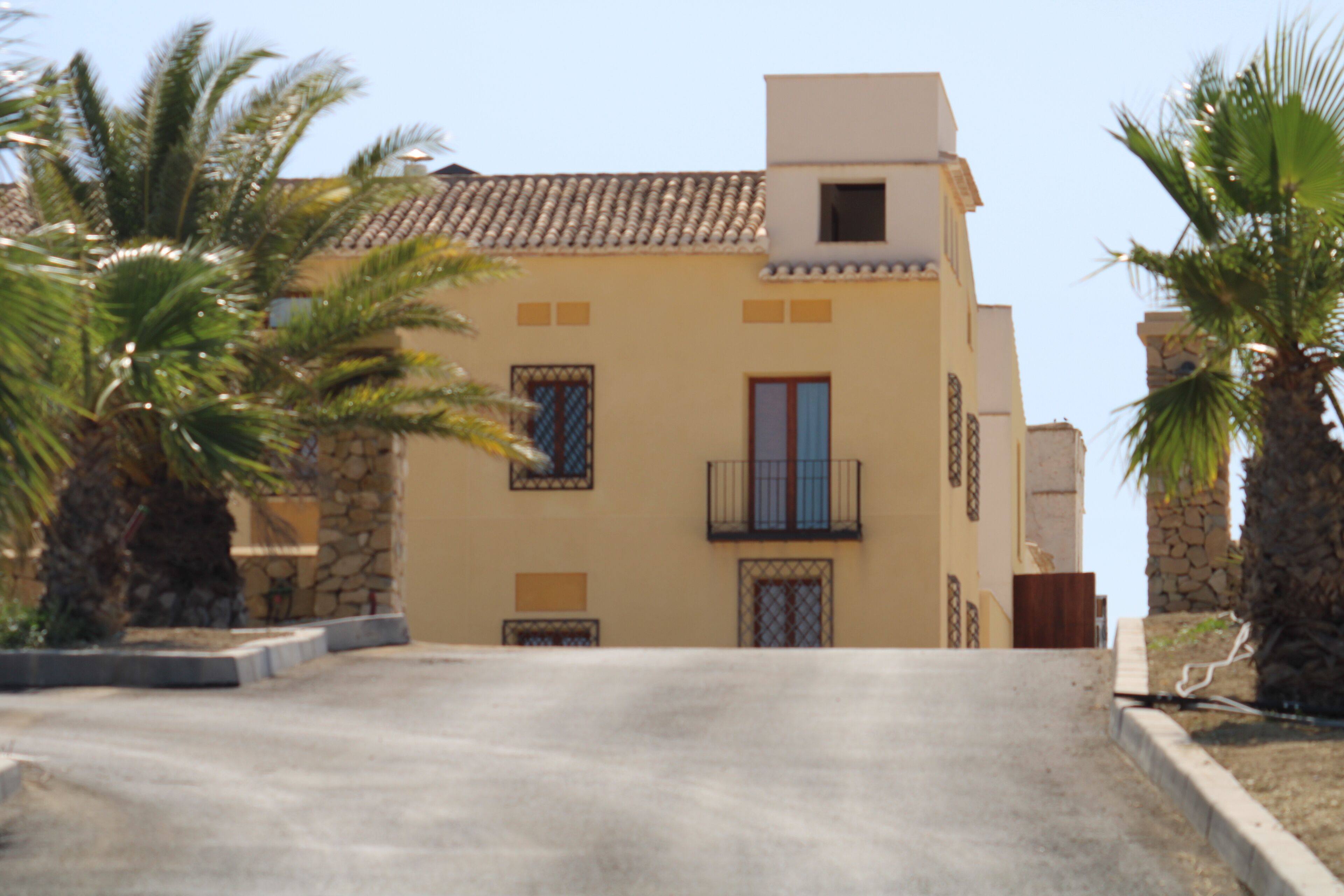 A building with a tiled roof, a balcony, and palm trees.