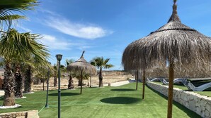 Un césped cuidado con palmeras y construcciones de techo de paja, evocando un ambiente de resort.