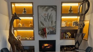 Una sala de estar moderna con chimenea, un sofá y elementos decorativos como estatuas y un cuadro.