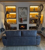 Uma sala de estar moderna com lareira, um sofá e objetos decorativos, incluindo estátuas e um quadro.