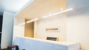 A reception area with a white reception desk, two wooden stools, a framed artwork on the wall, and a vent on the desk.