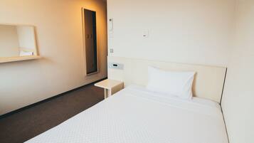 A hotel room with a large bed, a bedside table, a wall-mounted mirror, and a door.