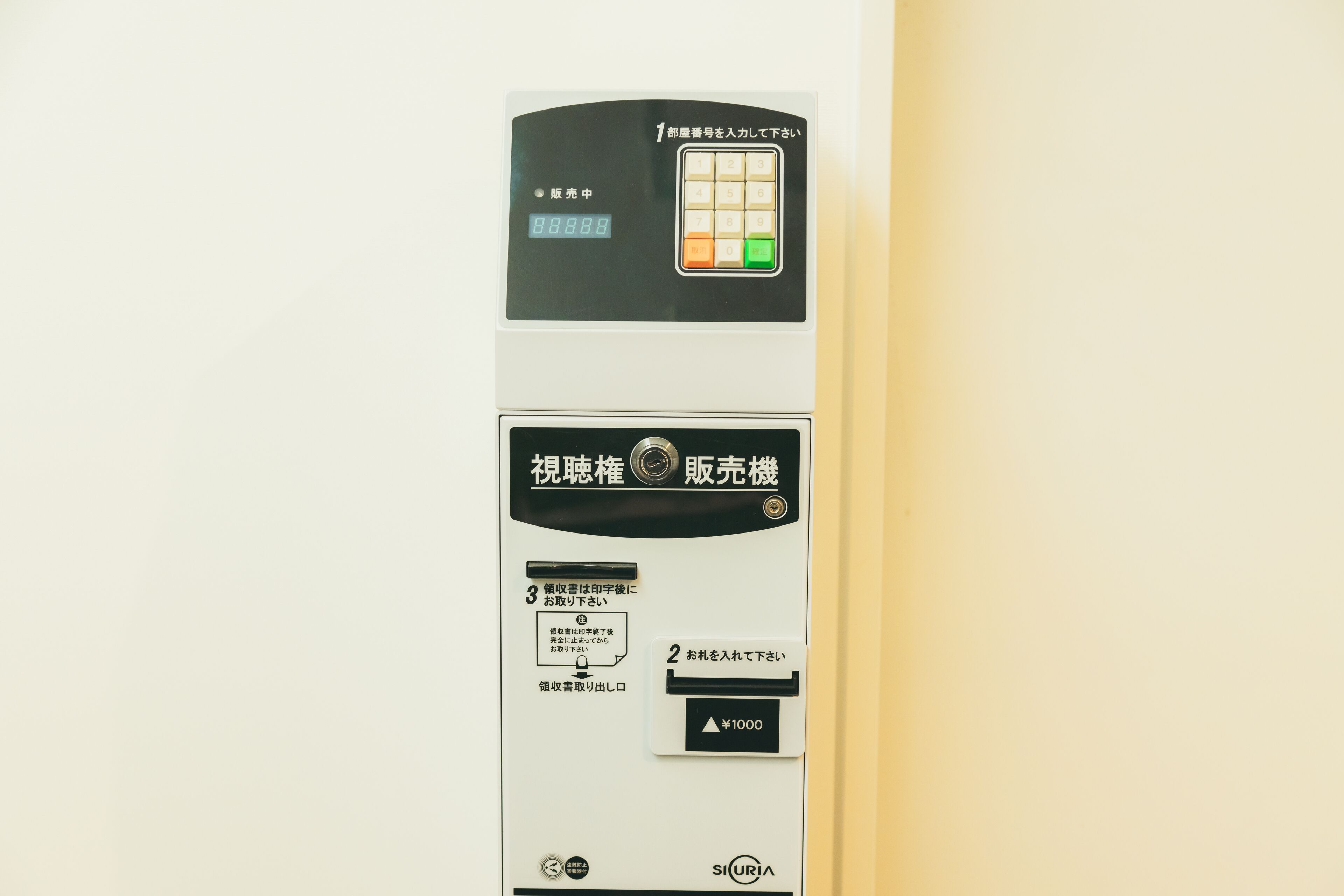 A security kiosk with a keypad and a card reader, featuring instructions in Japanese.