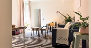 A living room with a sofa, a coffee table, a lamp, and a potted plant. - Charming Modern Apartment (Como)