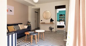 A modern living room with a sofa, two side tables, a patterned rug, and a large mirror on the wall. - Charming Modern Apartment (Como)