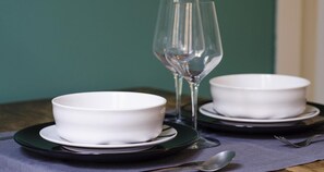Two white bowls on black plates with a clear glass stemmed wine glass between them. - Charming Modern Apartment (Como)