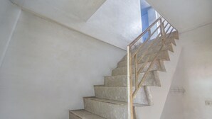 A spiral staircase with a wooden handrail and beige steps, leading to a higher floor. - Hotel O Borneo (Tondano)