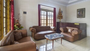 A reception area with two brown leather sofas, a wooden coffee table, and a reception desk. - Hotel O Borneo (Tondano)