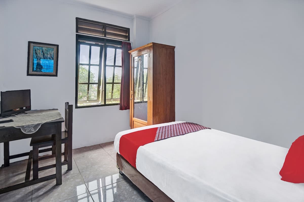 Quarto com cama, escrivaninha, cadeira, guarda-roupa e janela com cortinas.