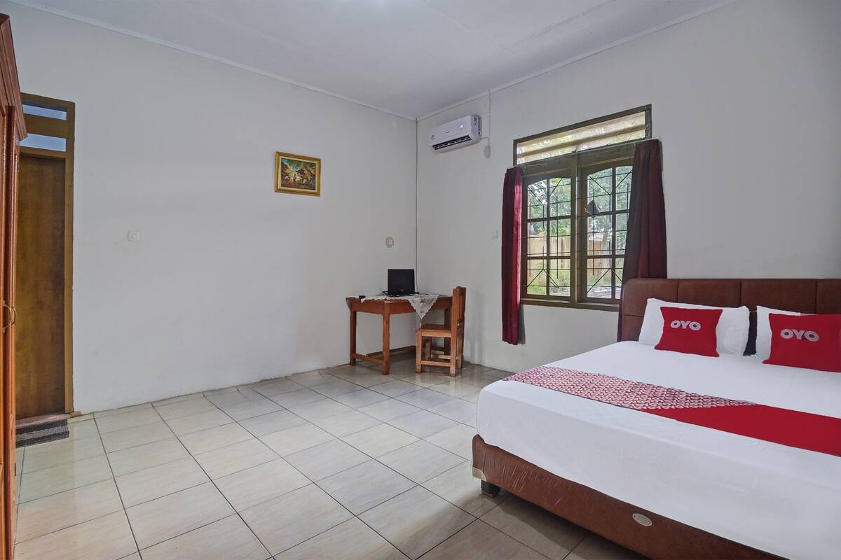 Um quarto com cama, escrivaninha e cadeira.