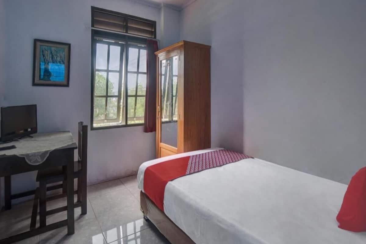Quarto com uma cama, escrivaninha, cadeira, guarda-roupa e janela.