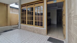 A building entrance with a tiled floor, a wooden door with glass panels, and a visible corridor inside. - Hotel O Borneo (Tondano)