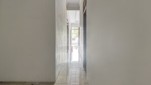 A narrow, well-lit hallway with tiled flooring and plain walls. - Hotel O Borneo (Tondano)