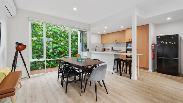 Une cuisine moderne dotée d’une grande fenêtre, de meubles en bois et d’un réfrigérateur noir.