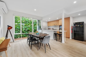 A modern kitchen with a large window, wooden cabinets, and a black refrigerator. - The Richmond House by Ready Set Stay - Family Friendly Holiday House, full linen (Richmond)