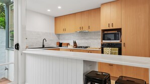 Une cuisine moderne avec des meubles blancs, un plan de travail blanc et un four à micro-ondes encastré.