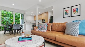 Un salon moderne avec un canapé en cuir marron, une table basse ronde et un coin repas comprenant une table et des chaises.
