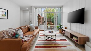 Un salon moderne avec un canapé en cuir marron, une table basse et un téléviseur fixé au mur.
