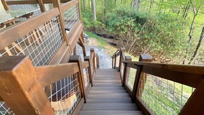 Una escalera de madera que desciende hacia una zona boscosa.