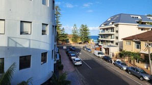 A street view with a modern building on the left and a residential area on the right. - Quaint 1BD on the Doorstep of Manly Beach (Manly)