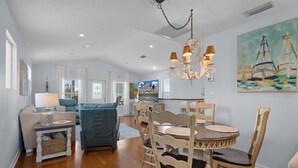 A spacious living area with a dining table, chairs, a sofa, and a chandelier. - KeyLime Downtown Gulf View-FREE Golf Cart for 2026 (Cedar Key)