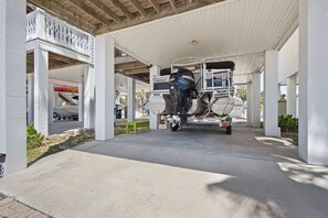 A covered parking area with a boat trailer and a motorboat.