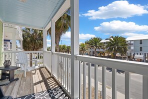 A wooden deck with white railings, a table, and chairs.