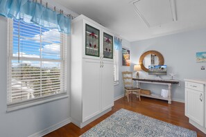 A room with a desk, chair, and a view through a window with blinds.