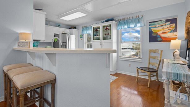 A kitchen with a bar area, wooden stools, and a dining table with chairs. - KeyLime Downtown Gulf View-FREE Golf Cart for 2026 (Cedar Key)