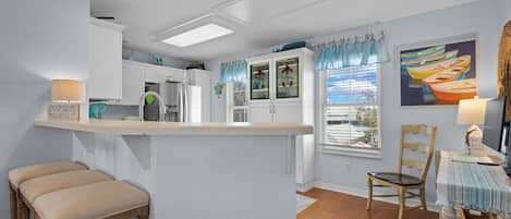A kitchen with a bar area, wooden stools, and a dining table with chairs.