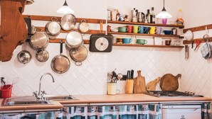 Une cuisine avec des casseroles suspendues, un fourneau et divers ustensiles.