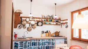 Une cuisine compacte avec un plan de travail en bois, des ustensiles de cuisine suspendus et une fenêtre offrant une belle vue.
