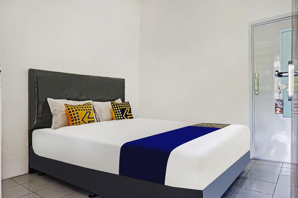 Ein Bett mit dunklem Kopfteil, weißer Bettwäsche und blauem Akzent.