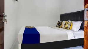 A bedroom with a bed, white walls, and a wooden door. - Hotel O Wisma Asri Putra Syariah (Ciampia)