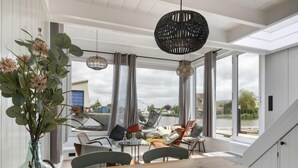 A modern dining area with a wooden table, chairs, and a vase of flowers. - Harboursuite 2 incl. motorboot by Interhome (Woudsend)
