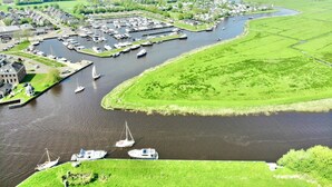 An aerial view of a riverside town with a marina, green fields, and residential areas. - Harboursuite Woudsend incl. motorboot by Interhome (Woudsend)