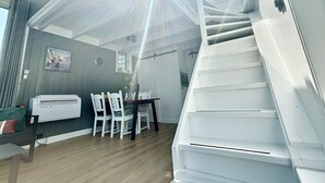 A modern interior with a staircase, a dining area, and a wall-mounted air conditioner. - Harboursuite Woudsend incl. motorboot by Interhome (Woudsend)
