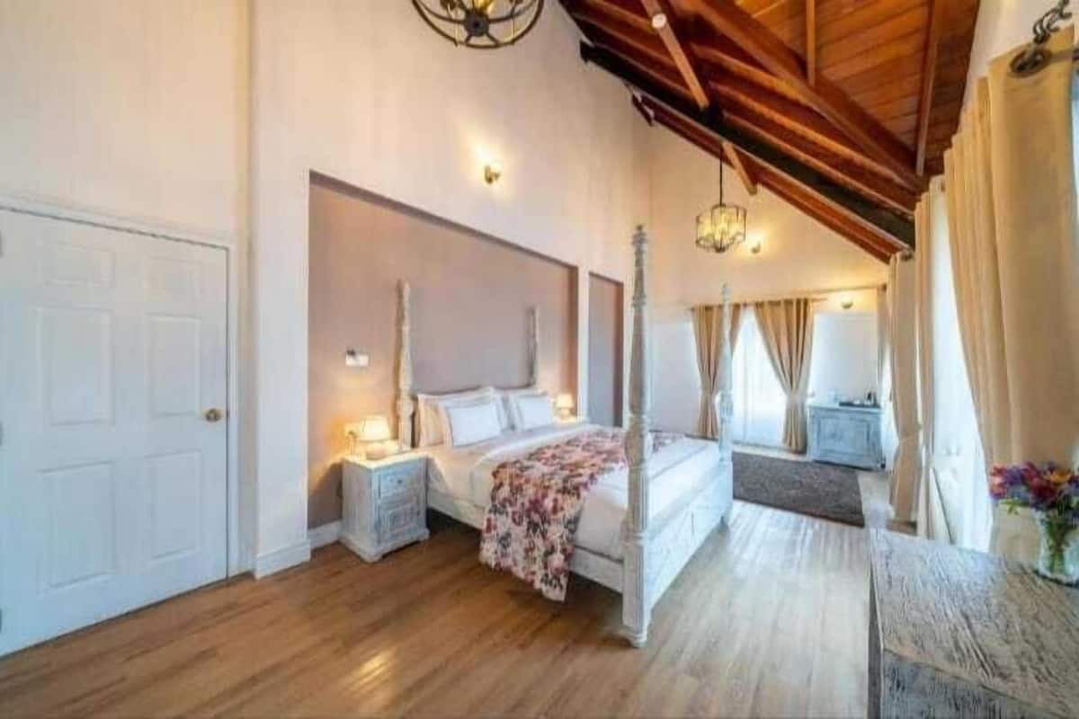 Ein geräumiges Schlafzimmer mit einem Himmelbett, Holzboden und einer schrägen Decke.