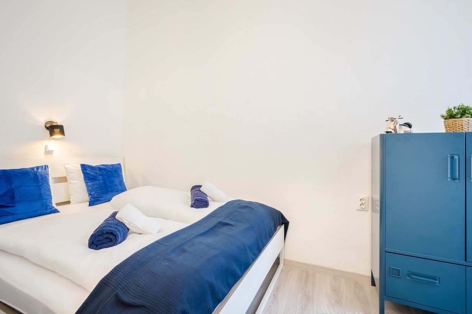 A bedroom with a bed, pillows, a bedside lamp, and a wardrobe.