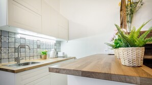Una cocina moderna con encimera de madera, armarios blancos, salpicadero de azulejos y un lavamanos integrado.