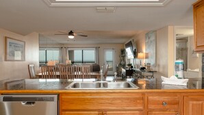 A modern kitchen with a dishwasher, wooden cabinets, and a large island with a sink.