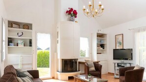 A spacious living room with a fireplace, a television, and comfortable seating. - Les Agapanthes by Interhome (Dinard)