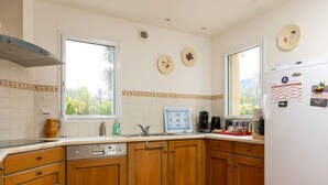 A kitchen with wooden cabinets, a dishwasher, a coffee maker, and a refrigerator. - Les Agapanthes by Interhome (Dinard)